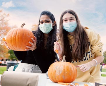 Two students enjoy carving pumpkins outside of Bryant.