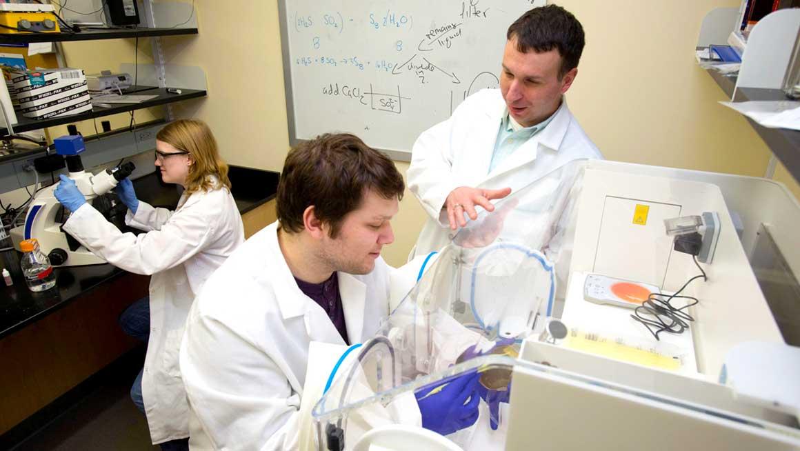 Bryant University Professor Chris Reid works with students in a research lab.
