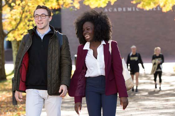 Two students walk down a path outside Bryant University.