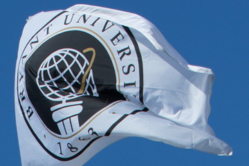 The Bryant University flag blowing in the wind against a blue sky.
