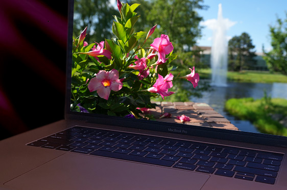 A laptop computer open to spring photo taken from a walkway at Bryant University.