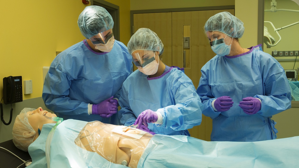 A group of Physician Assistant students work with a medical simulation dummy.