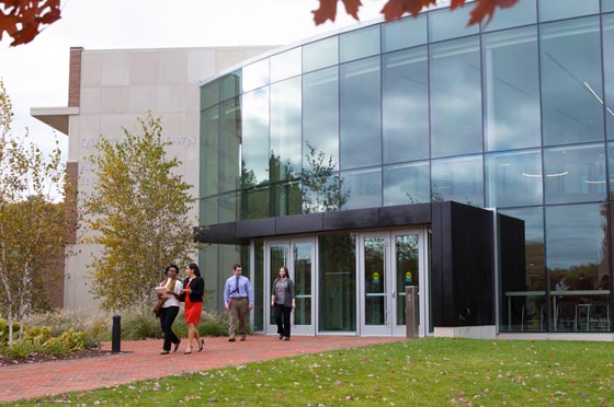 Four students walk out of the entrance to the Quinlan Brown Academic Innovation Center at Bryant University.