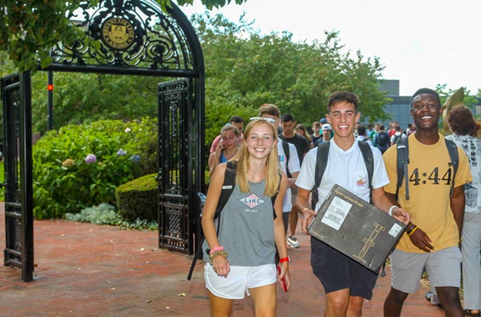 A trio of students walk near the Archway at Bryant University.