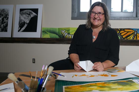 Valerie Carrigan, Lecturer sitting in her studio with drawings, paintings, prints, and artist books reflecting the intersection of the natural world and human spirit