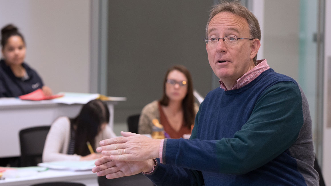 Bryant Professor Charles Cullinan speaks to students in a classroom.
