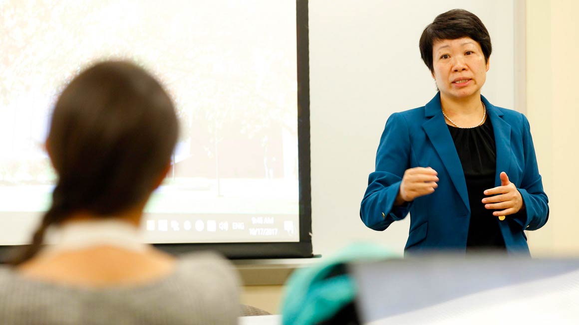 Bryant Professor Suhong Li lectures in a classroom.