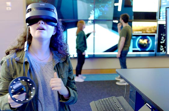 A student wears a virtual reality headset in the Data Visualization Lab at Bryant University.