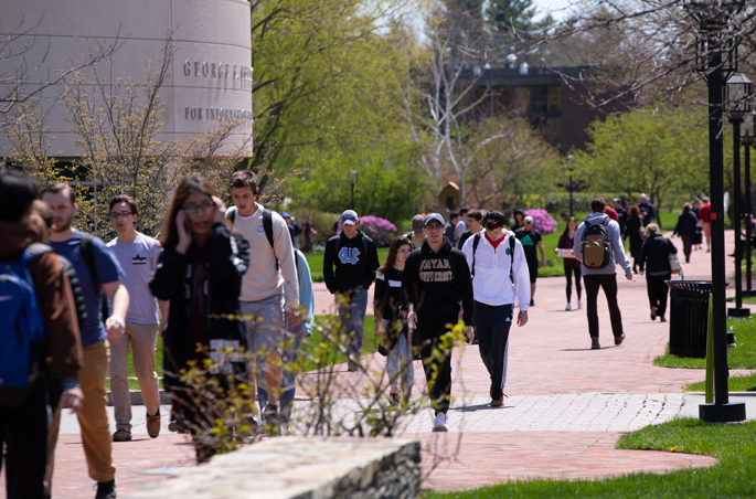 Students walk across campus on a sunny, spring day.