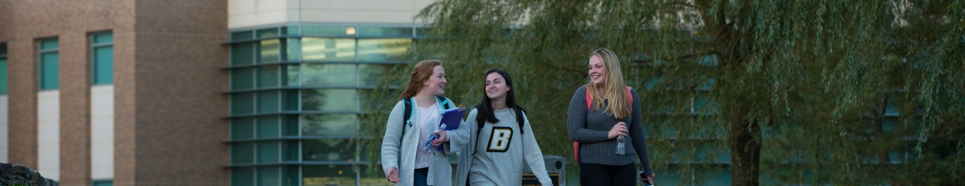 Three women students walk through campus