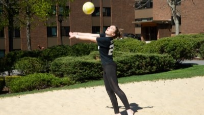 A student plays volleyball outdoors on campus.