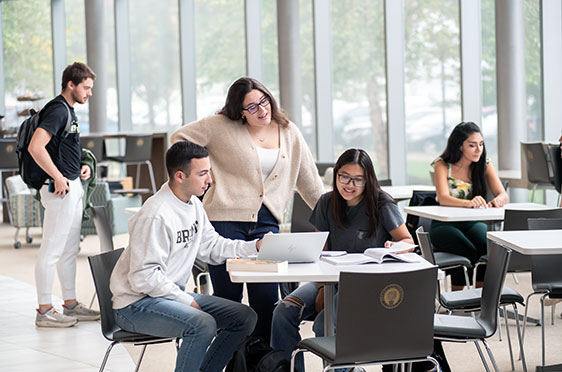 Two students sit at a desk and discuss an assignment at the Quinlan / Brown Academic Innovation Center at Bryant University.
