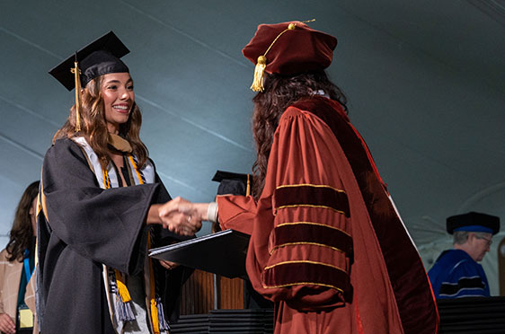 A student receives her diploma during commencement exercises at Bryant University.
