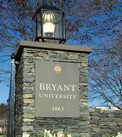     Sun shines through the Bryant University archway.
