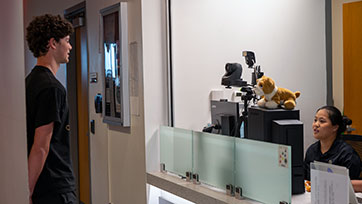 A Bryant University student readies to get his ID photo taken at the Information Center inside the Fisher Student Center.