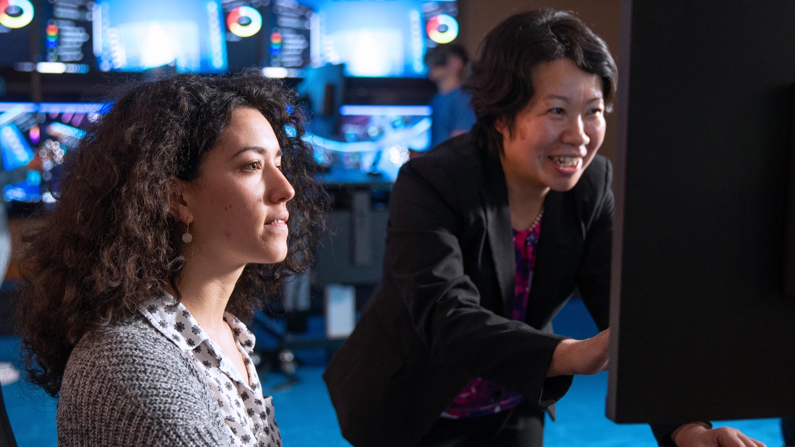 Bryant University Professor Suhong Li works with a student inside a data visualization lab.