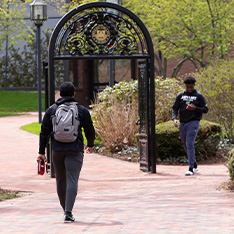 A Bryant University student walks toward the archway.